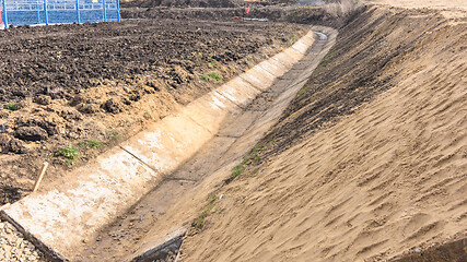 Image showing Construction of a drainage ditch along a road near an industrial facility