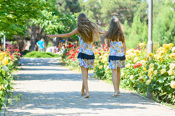 Image showing Two little sisters are walking in a beautiful flower city park