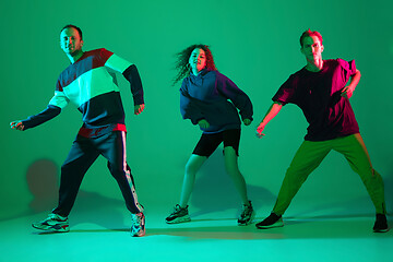 Image showing Stylish men and woman dancing hip-hop in bright clothes on gradient background at dance hall in neon light