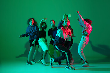 Image showing Stylish men and woman dancing hip-hop in bright clothes on gradient background at dance hall in neon light