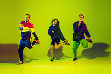 Image showing Stylish men and woman dancing hip-hop in bright clothes on gradient background at dance hall in neon light