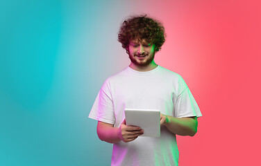 Image showing Caucasian young man\'s portrait on gradient studio background in neon