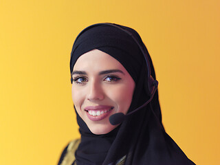 Image showing portrait of muslim woman with headset on yellow background