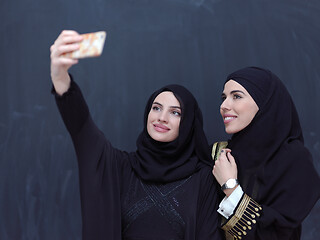 Image showing muslim women taking selfie picture in front of black chalkboard