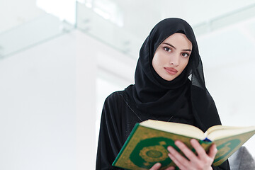 Image showing young muslim woman reading Quran at home