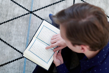 Image showing young muslim man reading Quran at home
