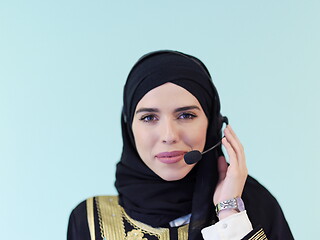 Image showing portrait of muslim woman with headset on cyan background