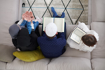 Image showing muslim family reading Quran and praying at home top view