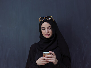 Image showing young muslim woman wearing sunglasses using smartphone