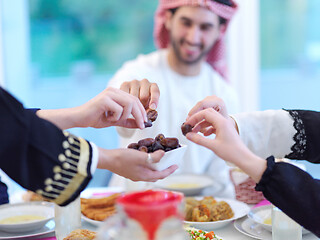 Image showing Muslim family having Iftar dinner eating dates to break feast