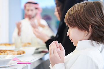 Image showing little muslim boy praying with family before iftar dinner