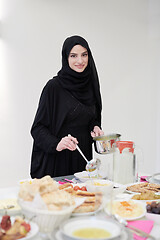 Image showing young muslim girl serving food on the table for iftar dinner