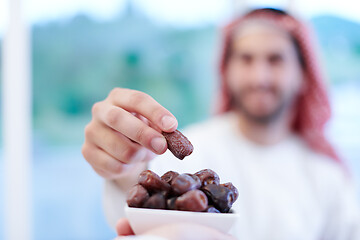 Image showing Muslim family having Iftar dinner eating dates to break feast