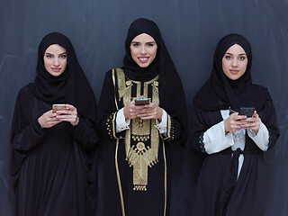 Image showing muslim women using mobile phone in front of black chalkboard