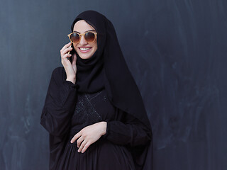 Image showing young muslim woman wearing sunglasses using smartphone