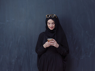 Image showing young muslim woman wearing sunglasses using smartphone