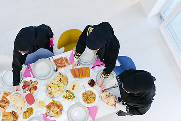 Image showing young muslim girls serving food on the table for iftar dinner to