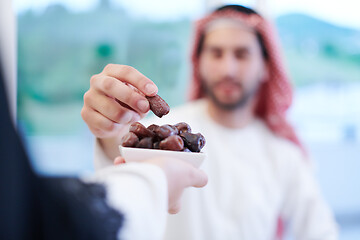 Image showing Muslim family having Iftar dinner eating dates to break feast