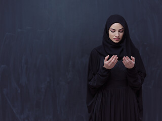 Image showing muslim woman making traditional prayer to God in front of black 