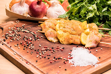 Image showing raw chicken skewers marinated with lemon on a wooden board