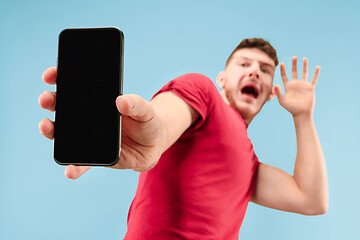 Image showing Portrait of the scared man with phone on blue