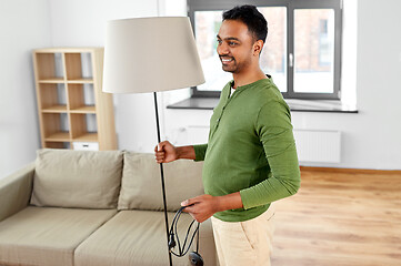 Image showing happy indian man holding floor lamp at home