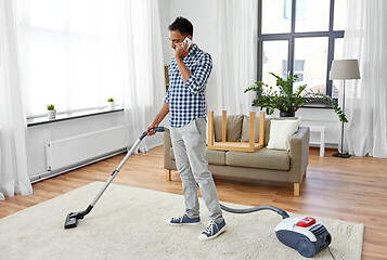 Image showing man with vacuum cleaner calling on cell at home