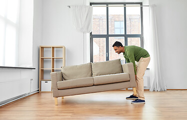 Image showing happy indian man moving sofa at home