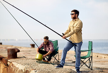 Image showing happy friends with fishing rods on pier