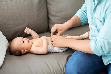 Image showing middle aged father changing baby\'s diaper at home