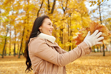 Image showing happy woman having fun with leaves in autumn park