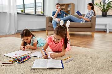 Image showing happy sisters drawing and doing homework at home