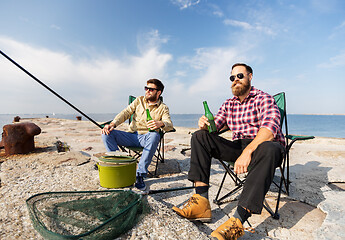 Image showing male friends fishing and drinking beer on sea pier