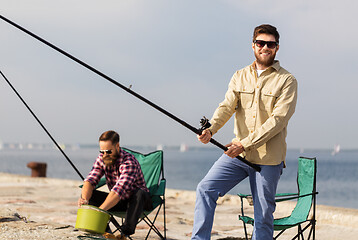 Image showing male friends with fishing rods on sea pier