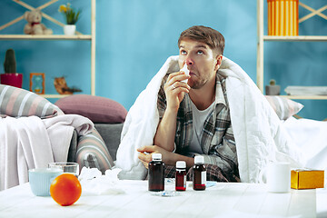 Image showing Bearded sick man with flue sitting on sofa at home. Illness, influenza, pain concept. Relaxation at Home. Healthcare Concepts.