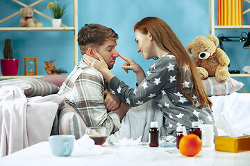 Image showing Sick man with fever lying in bed having temperature girl take care for him