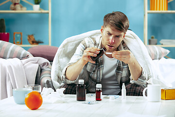 Image showing Bearded sick man with flue sitting on sofa at home. Illness, influenza, pain concept. Relaxation at Home. Healthcare Concepts.