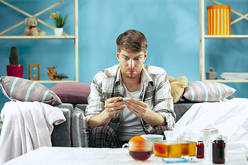 Image showing Bearded sick man with flue sitting on sofa at home. Illness, influenza, pain concept. Relaxation at Home. Healthcare Concepts.