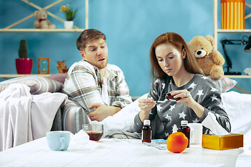 Image showing Sick man with fever lying in bed having temperature girl take care for him