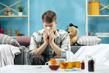 Image showing Bearded sick man with flue sitting on sofa at home. Illness, influenza, pain concept. Relaxation at Home. Healthcare Concepts.