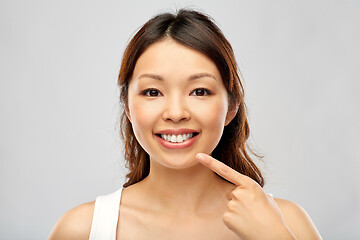 Image showing happy smiling young asian woman touching her face