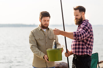 Image showing male friends with fish and fishing rods on pier