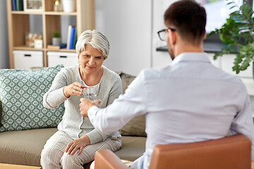 Image showing psychologist giving glass of water to senior woman