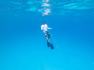 Image showing Underwater view of man free diving in blue ocean.