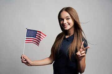 Image showing Happy female holding United States of America flag and gesturing Victory