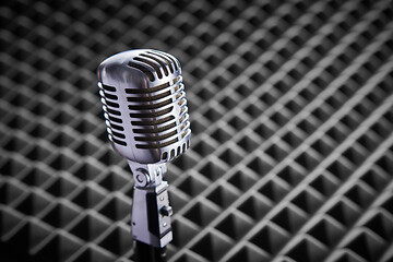Image showing Closeup of chrome retro condenser microphone on acoustic foam panel background