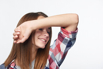 Image showing Smiling girl with raised hand shielding eyes