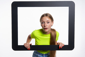 Image showing Teen girl peeking through digital tablet frame