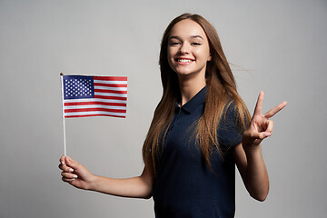 Image showing Happy female holding United States of America flag and gesturing Victory