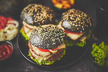 Image showing Black double burgers with vegetables and cheese